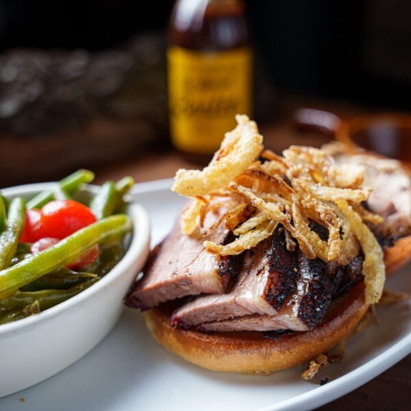 brisket sandwich from salt + smoke with fried onions and a side of tomato salad.